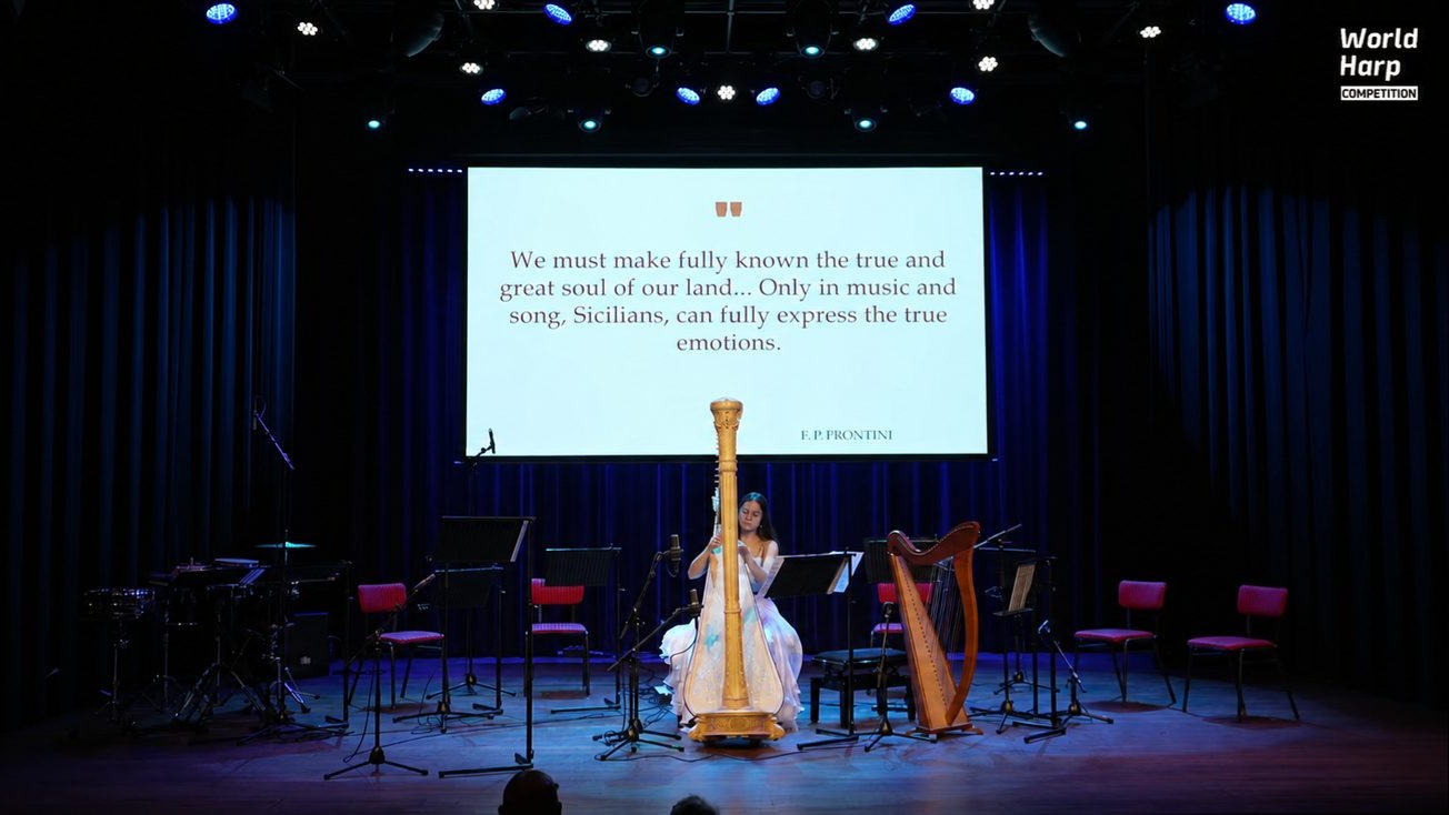 Francesca Campo na World Harp Competition, za nią wyświetlony cytat Frontiniego